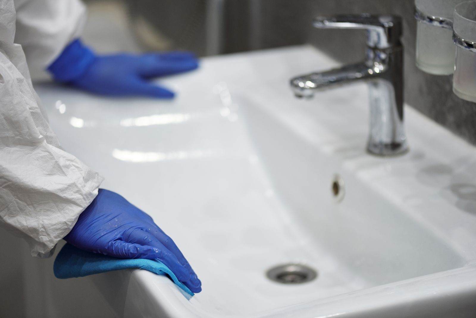 Limpeza detalhada de um lavatório com luvas de proteção